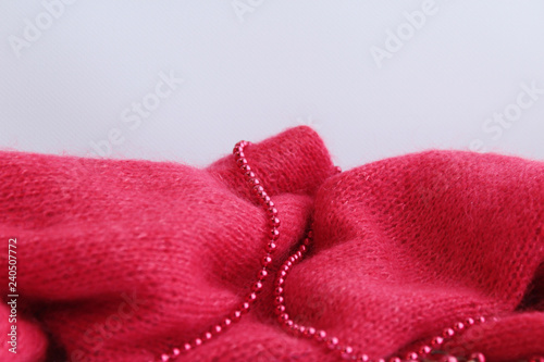  Handmae kitted woolen red scarf  isolated on a light background  decorated with beads of red. View directly and copy space.