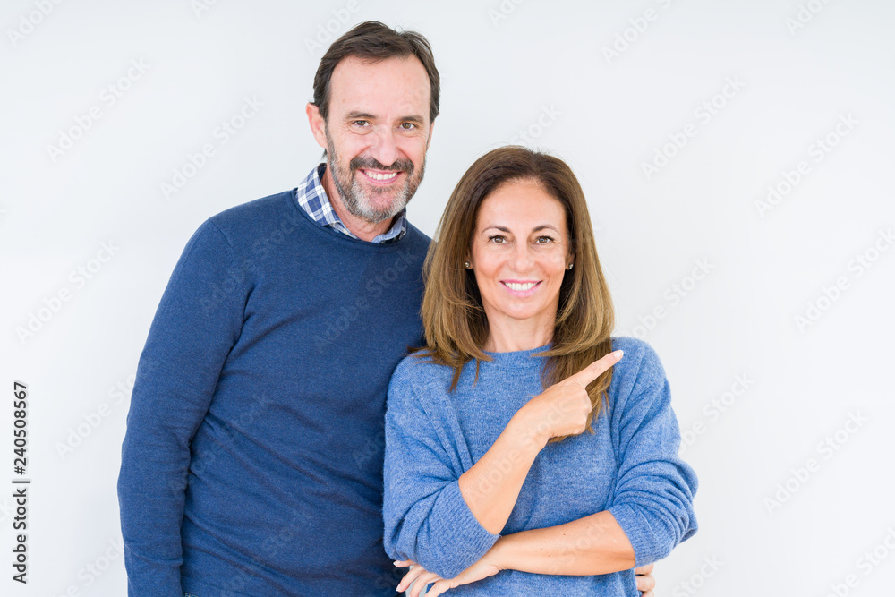 Beautiful middle age couple in love over isolated background cheerful with a smile of face pointing with hand and finger up to the side with happy and natural expression on face Beautiful middle age couple in love over isolated background cheerful with a smile of face pointing with hand and finger up to the side with happy and natural expression on face