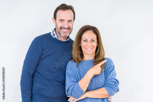Beautiful middle age couple in love over isolated background cheerful with a smile of face pointing with hand and finger up to the side with happy and natural expression on face