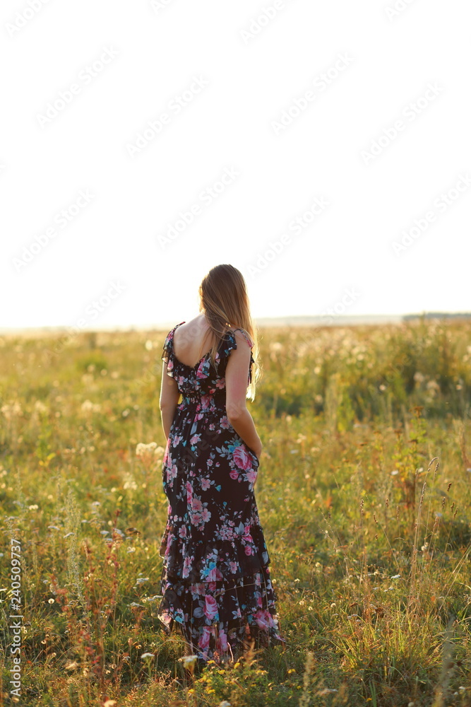 woman in sundress in field of flowers at sunset vertical woman in sundress in field of flowers at sunset vertical