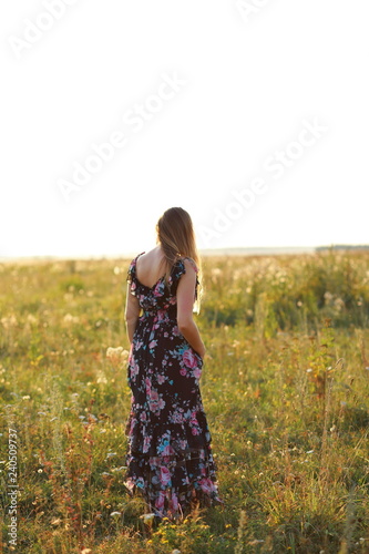 woman in sundress in field of flowers at sunset vertical