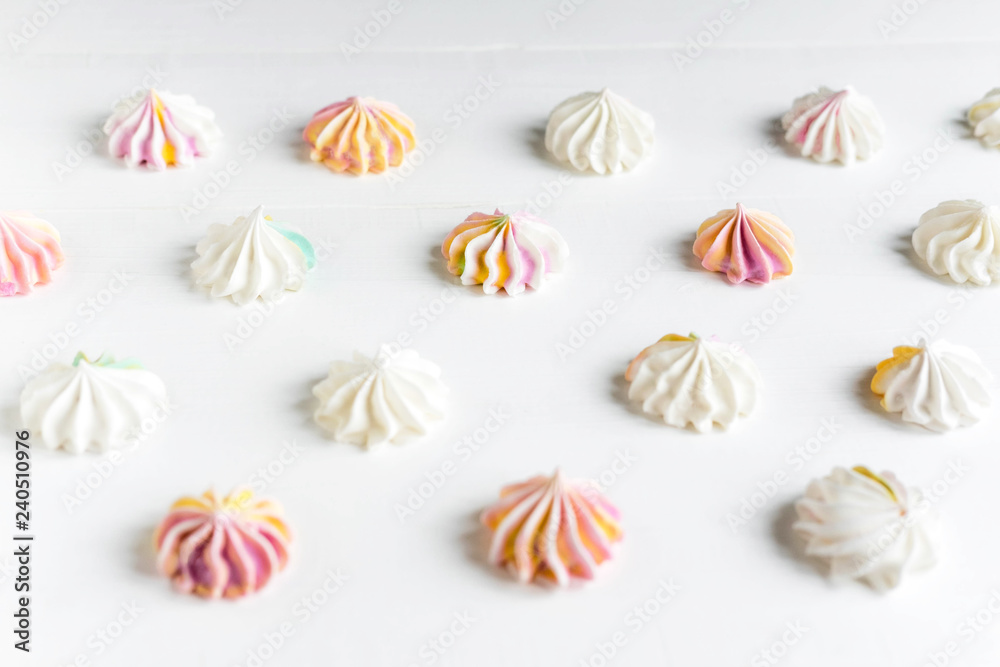Pattern with meringues on a white wooden background. Multicolored meringues on a white background. Basis for confectionery banner, cafe, sweet shop. Meringue banner Pattern with meringues on a white wooden background. Multicolored meringues on a white background. Basis for confectionery banner, cafe, sweet shop. Meringue banner