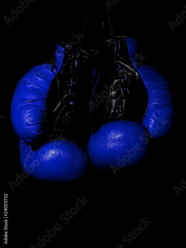 Old leather blue boxing gloves hanging in the dark
