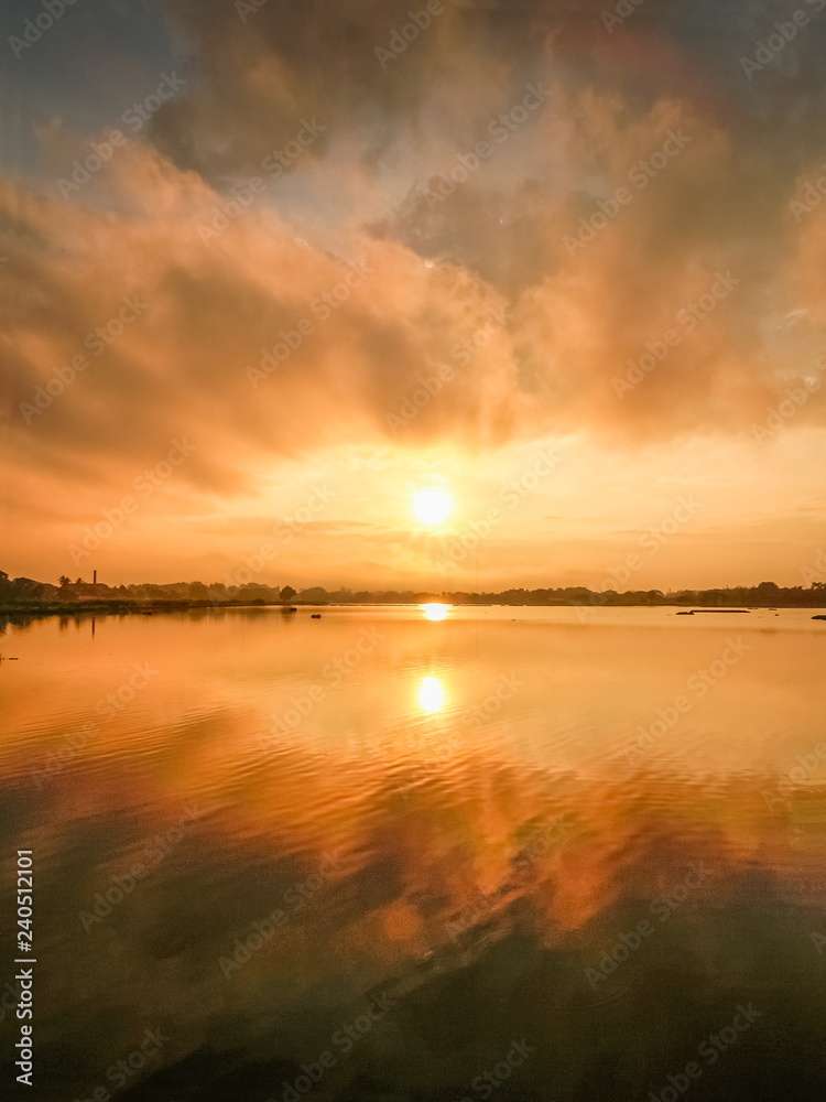 Lake view morning of dark cloud moving above the lake with reflection on the water and colorful of yellow sun light in the sky background, sunrise at Kwan Phayao Lake, Phayao, northern of Thailand. Lake view morning of dark cloud moving above the lake with reflection on the water and colorful of yellow sun light in the sky background, sunrise at Kwan Phayao Lake, Phayao, northern of Thailand.