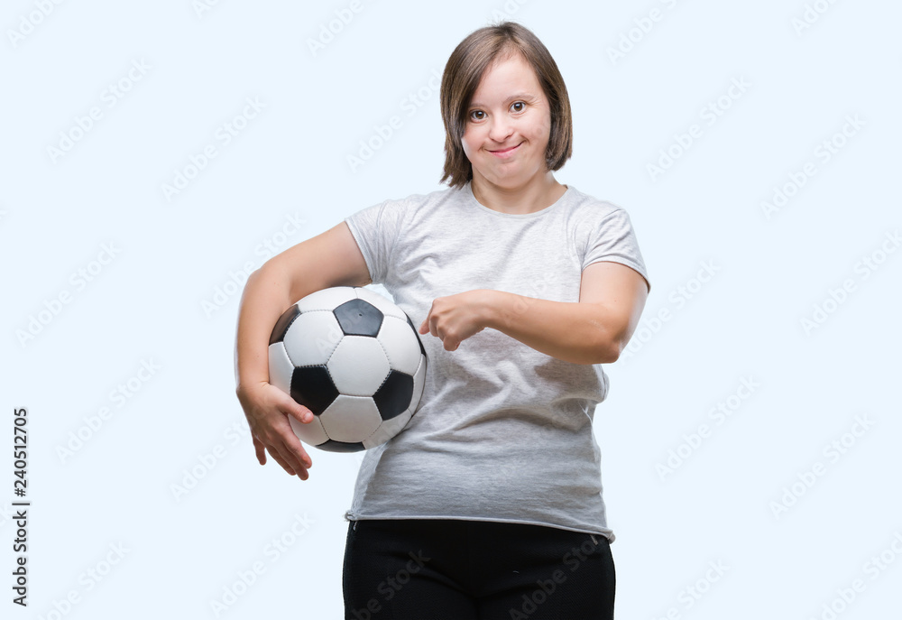 Young adult woman with down syndrome holding soccer football ball over isolated background very happy pointing with hand and finger