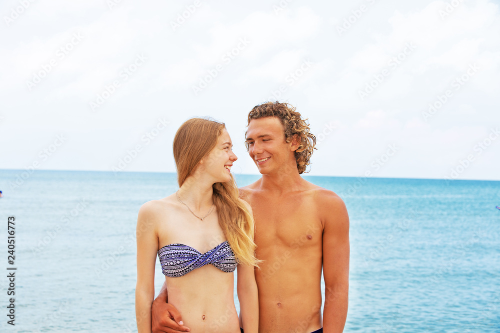 Portrait of young couple in love at beach and enjoying time being together. Young couple having fun on a sandy coast.