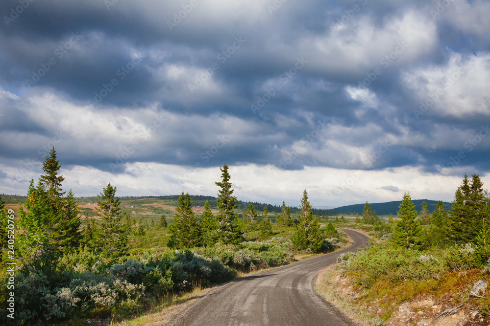 Rain clouds gloomy sky over winding scenic country road in Oppland Norway Scandinavia