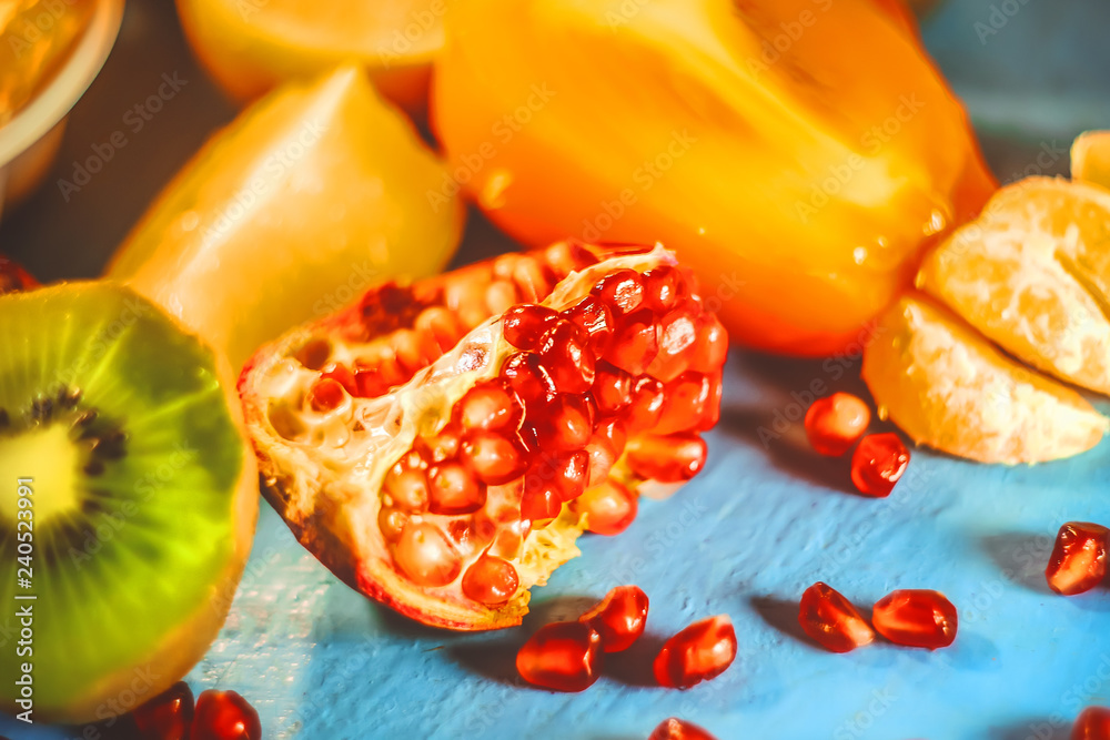 cut scitrus fruits. orange, pomegranate, mandarin, persimmon, kiwi. on a blue wooden board. cut scitrus fruits. orange, pomegranate, mandarin, persimmon, kiwi. on a blue wooden board.