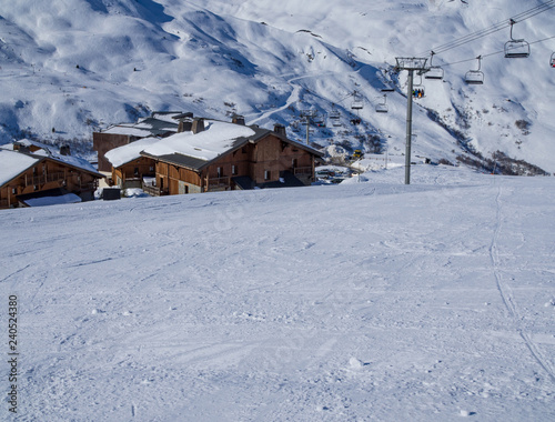 Meribel, France - February, 2018: Wooden Houses in Meribel ski resort. Skiers and snow slopes, beautiful sunny day.