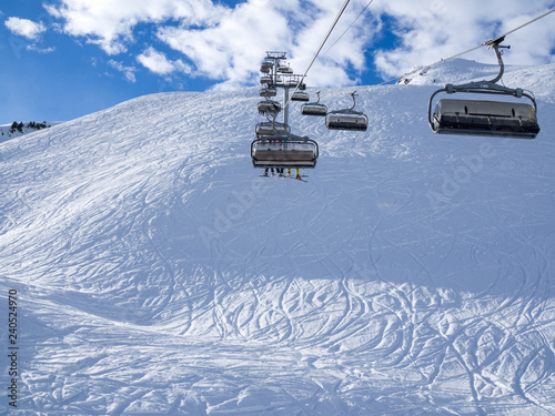 Skilift covered with ice and snow slopes in Courchevel in a sunny winter day, France, february 2018.