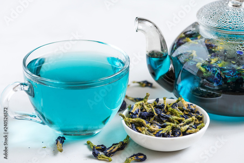 Butterfly pea flower blue tea in a cup with teapot on white marble table. Healthy detox herbal drink
