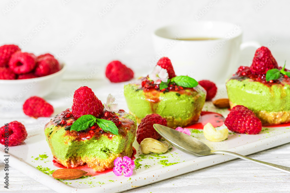 green matcha vegan raw cakes with raspberries, mint, nuts and cup of coffee. healthy delicious food