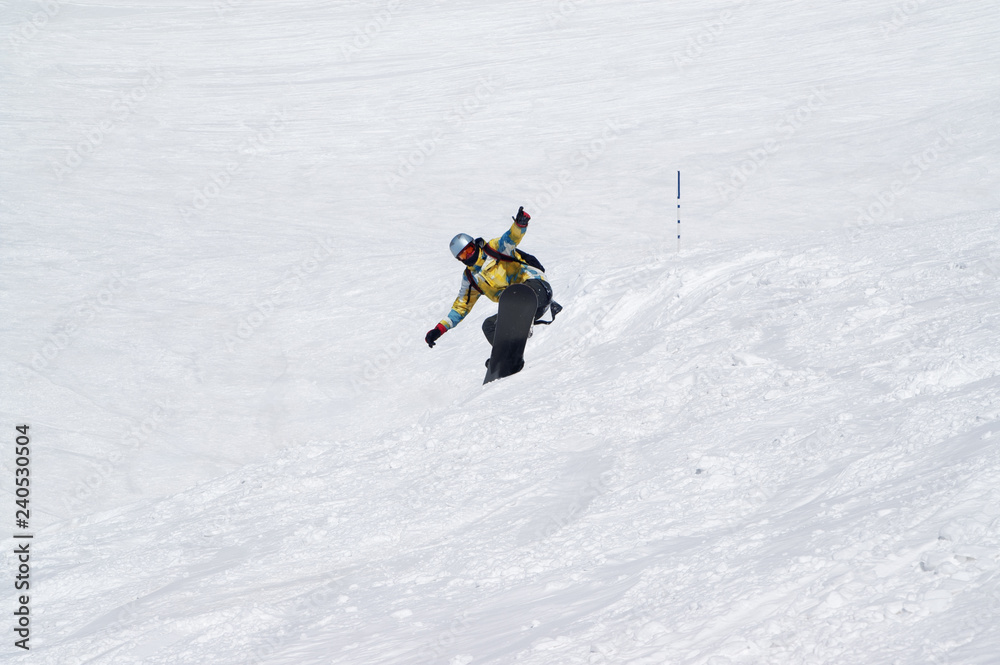 Snowboarder jumping on snowy ski slope at high winter mountains