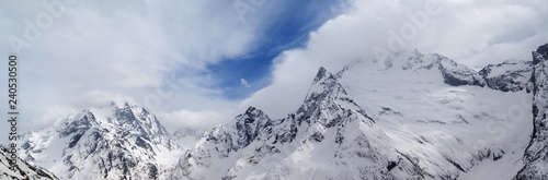 Panorama of gray high mountain peaks covered with ice © BSANI