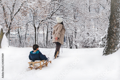 Young, beautiful mom and her cute little boy enyoing winter, sledding photo