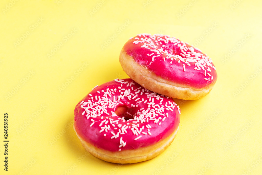 Two delicious pink donuts with sprinkle on bright yellow background Two delicious pink donuts with sprinkle on bright yellow background