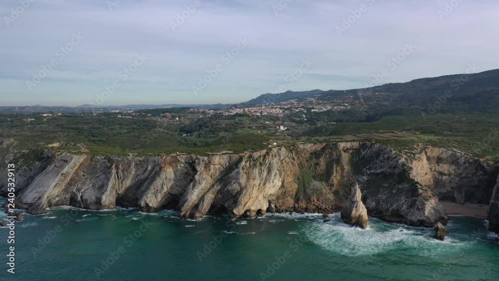 Aerial west Portugal coastline flight over rocks sticking out of the water near Ursa beach Aerial west Portugal coastline flight over rocks sticking out of the water near Ursa beach