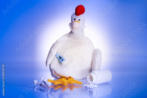 Rag doll of a chicken with face mask, thermometer, pills and syringes, symbolizing bird flu or avian flu. photo
