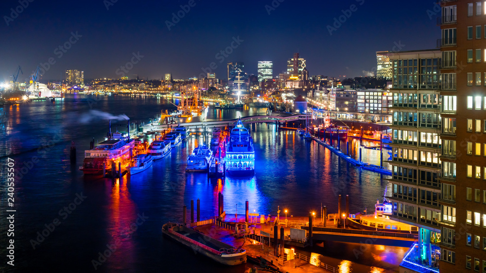 Hamburg Harbor and the  Harbor District in Hamburg, Germany, at night. View of the river Elbe and the pier Ueberseebruecke.