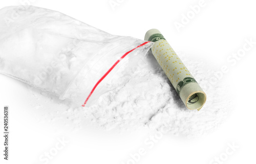 Cocaine in plastic bag and rolled money bill on white background