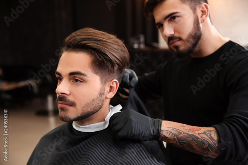 Professional hairdresser preparing client for shaving at barbershop