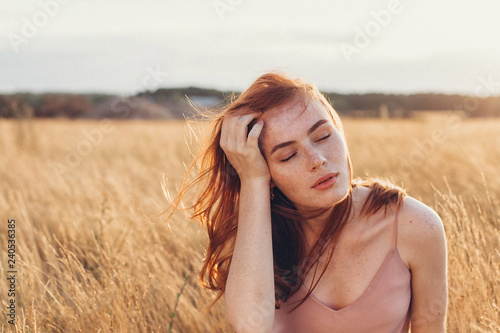 Outdoor portrait of young attractive ginger girl with freckles and lond hair. Natural beauty, casual, freedom concept photo