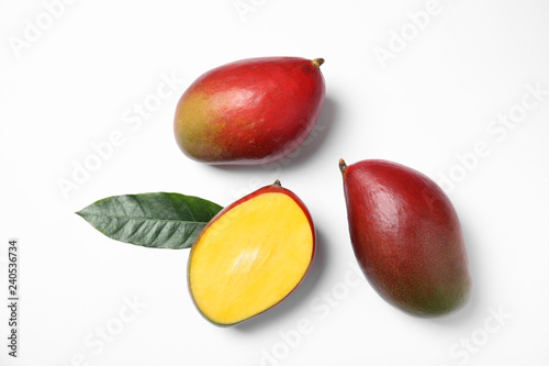 Tropical cut and whole mango with green leaf isolated on white, flat lay