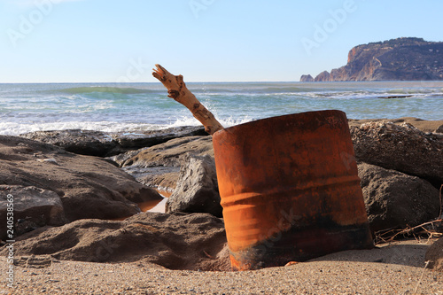 Barrel with log on the rocky beach with Bedesten Alanya fortress on background. photo