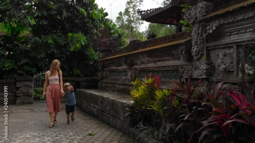 Slowmotion steadicam shot of young woman and hel littl son walking around the Pura Gunung Lebah temple in Ubud on the Bali island photo