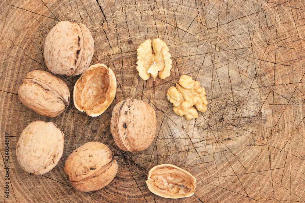 A few walnuts on a wooden surface. A broken nut with a shell and a kernel. Autumn harvest. Close-up. View from above. A few walnuts on a wooden surface. A broken nut with a shell and a kernel. Autumn harvest. Close-up. View from above.