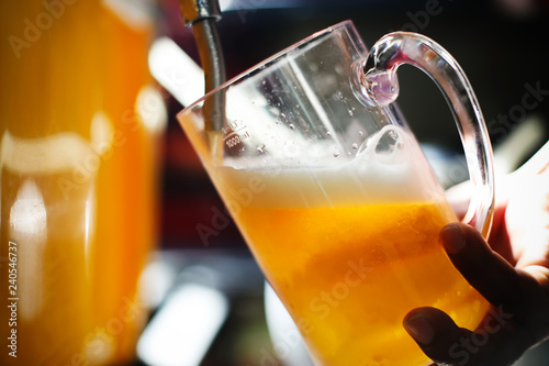 Close-up of barman hand at beer tap pouring a draught lager beer serving in the restaurant or pub.