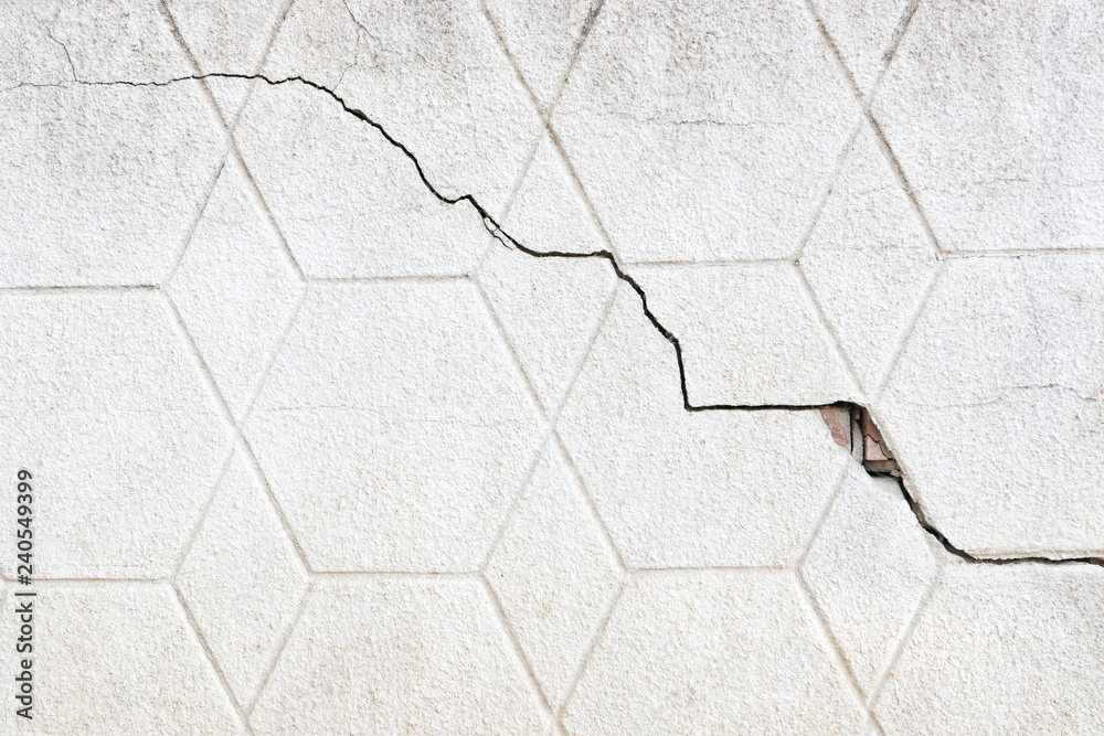 Obraz premium The texture of the surface of the old gray wall with a crack. Grunge background and wallpaper with space for text or image. Empty template and mockup for designers.