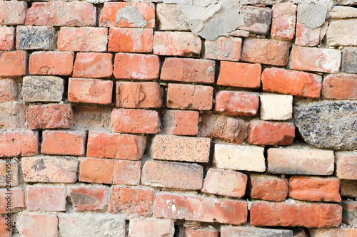 Dilapidated wall of old red bricks and stones. The texture of the brickwork. Grunge background. Template and mockup for designers.