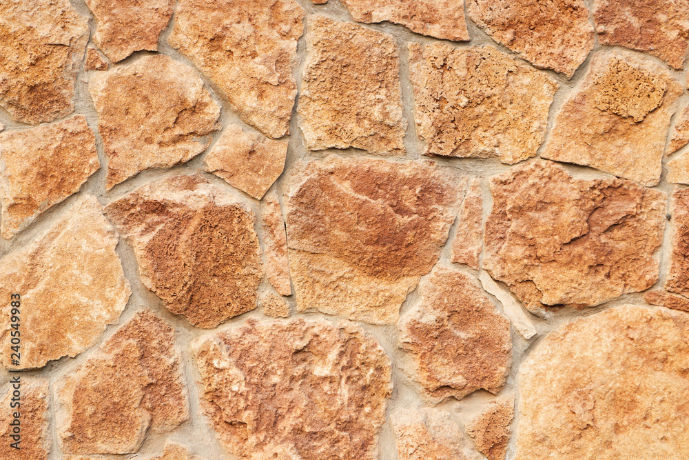 Decorative beige facing stone on the wall. The texture of the wall of the old stone. Background and wallpaper. Close-up. Decorative beige facing stone on the wall. The texture of the wall of the old stone. Background and wallpaper. Close-up.