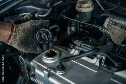 Car mechanic is checking engine condition. Engine oil  radiator  battery and throttle cable in the garage.