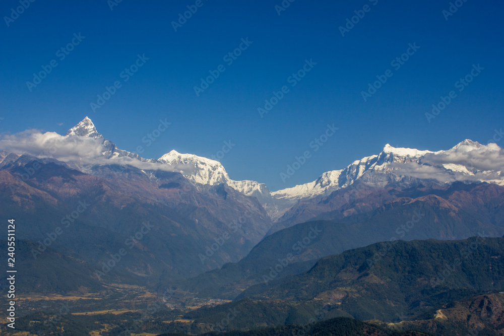 Annapurna and Machapuchare Mountains in Nepal Himalayas. snowy peaks of mountains in a valley with green slopes and clear blue sky