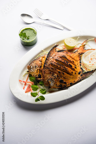 Tandoori Pomfret fish cooked in a clay oven and garnished with lemon , mint, cabbage and carrot salad. Selective focus