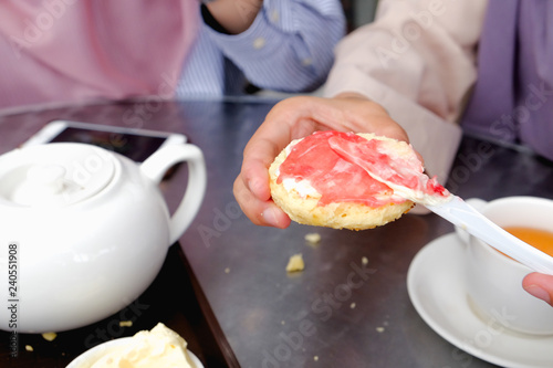 Фотография Young muslim woman sweep the strawberry jam on scone at the strawberry farm at Cameron Highland