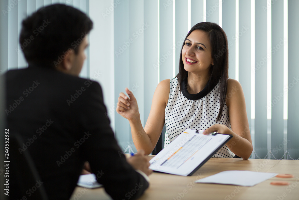 Smiling young businesswoman showing contract to partner. Young Caucasian manager having meeting with client, explaining agreement to him. Partnership and meeting concept