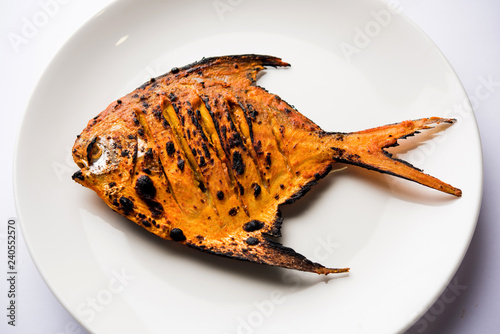 Tandoori Pomfret fish cooked in a clay oven and garnished with lemon , mint, cabbage and carrot salad. Selective focus photo