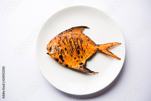Tandoori Pomfret fish cooked in a clay oven and garnished with lemon , mint, cabbage and carrot salad. Selective focus photo