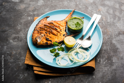 Tandoori Pomfret fish cooked in a clay oven and garnished with lemon , mint, cabbage and carrot salad. Selective focus photo