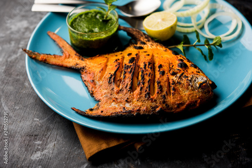 Tandoori Pomfret fish cooked in a clay oven and garnished with lemon , mint, cabbage and carrot salad. Selective focus photo