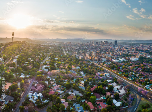 Aerial panorama of Pretoria city skyline at sunset. Jacaranda trees in suburb of Muckleneuk blooming. Telkom tower, Sunnyside apartment buildings and central business district behind.  photo