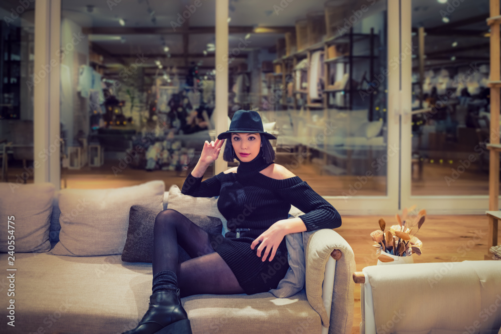 Obraz premium girl posing on a white sofa in a black dress