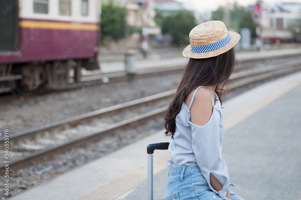 woman traveler at train station; portrait of asian woman traveler waiting train ride at train station platform; vacation, solo travel or holiday alone concept; woman 20s adult model
