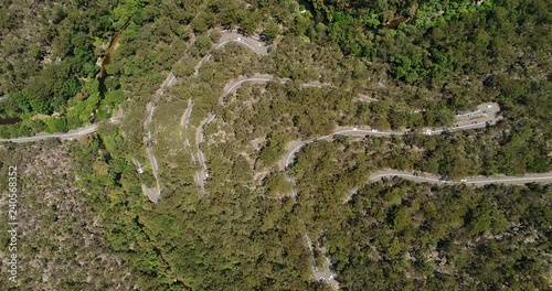 Multiple sharp turns on serpentine Galston road with car traffic crossing Berowra creek in woodlands national park of Australia.
 photo