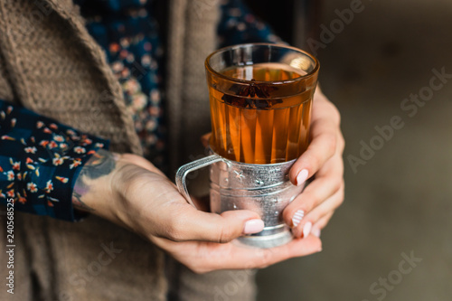 A glass with hot grog in woman s hands