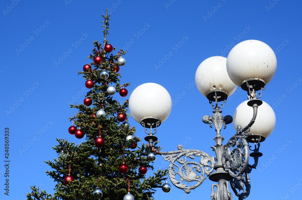 Old street lamp in Florence at Piazzle Michelangelo, with Christmas tree and blue sky. Italy