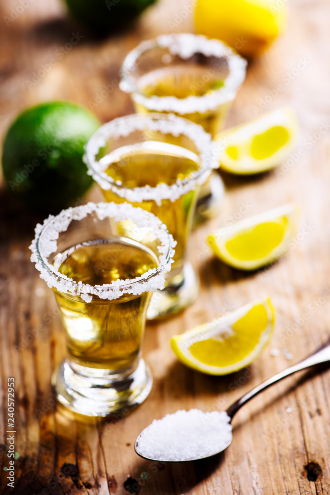 Golden mexican tequila in shot glass with lime and salt on vintage wooden table. Golden mexican tequila in shot glass with lime and salt on vintage wooden table.